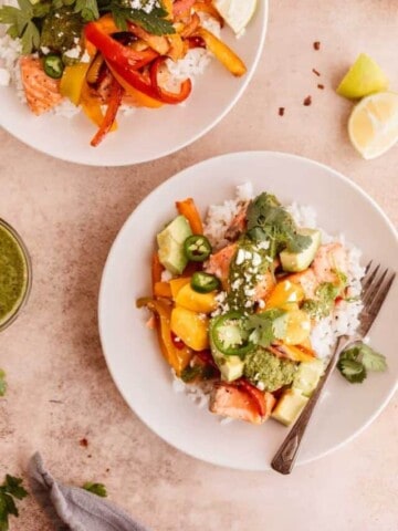 Salmon and rice bowl with mango, avocado, peppers, chimichurri and lime in off white bowls.