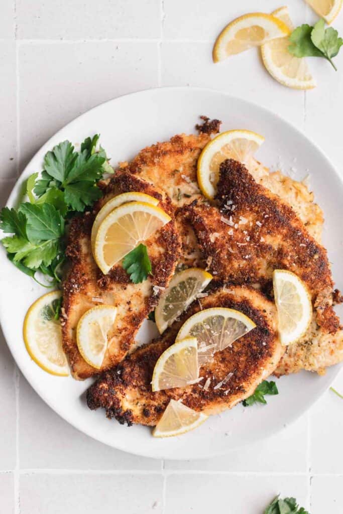 Lemon chicken on a plate with lemon slices and parsley.