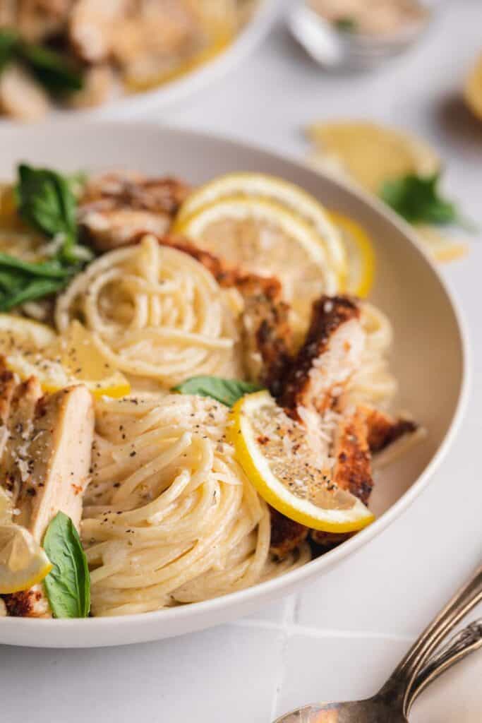 A bowl of spaghetti with lemon sauce and lemon chicken. 