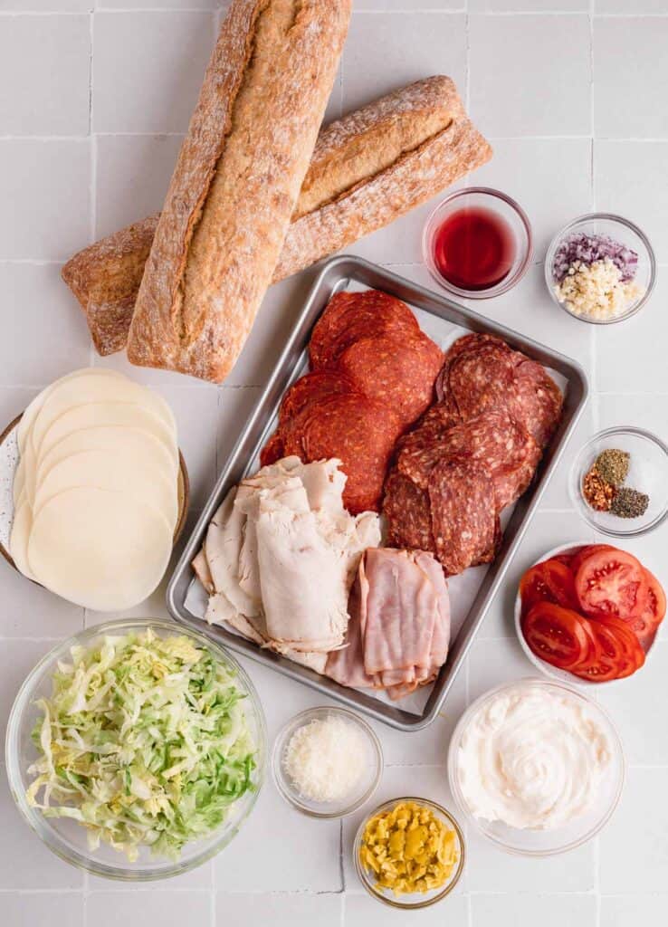 Crusty bread, pepperoni, turkey, ham, soppressata, lettuce, provolone, mayo, salt, pepper, tomatoes, pepperoncinis, red wine vinegar and garlic.