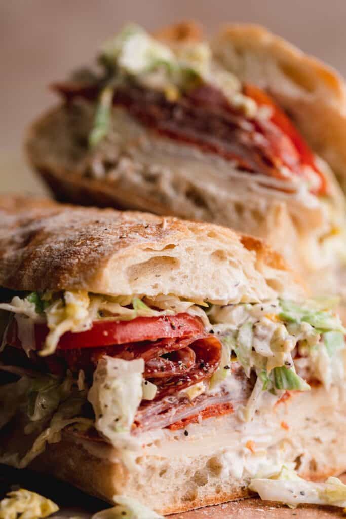Close up of the sandwich with the Italian meats, provolone, tomato and lettuce salad.
