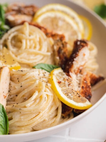 A bowl of Lemon Chicken Pasta with basil and lemon slices.