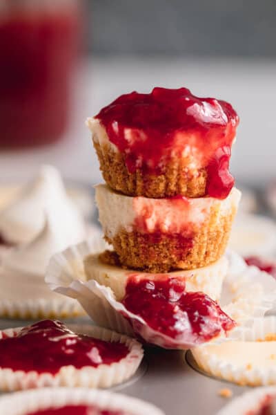 A stack of mini cheesecakes with strawberry compote on top and dripping down the front.