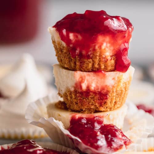 A stack of mini cheesecakes with strawberry compote on top and dripping down the front.