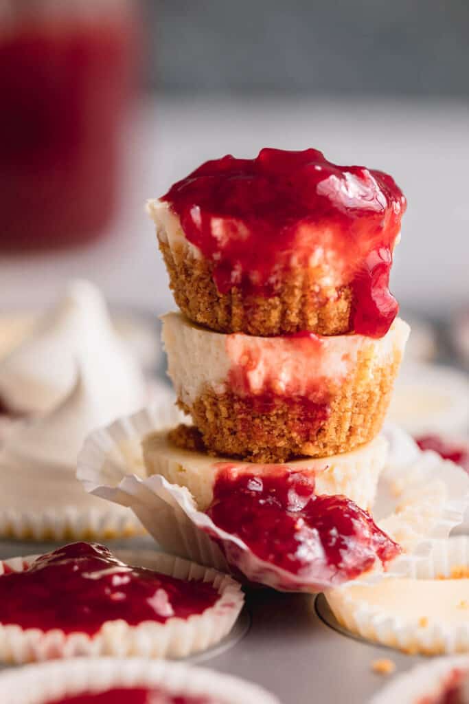 A stack of mini cheesecakes with strawberry compote on top and dripping down the front. 