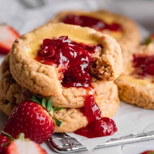 A stack of strawberry cheesecake cookies with strawberry compote dripping down the front.