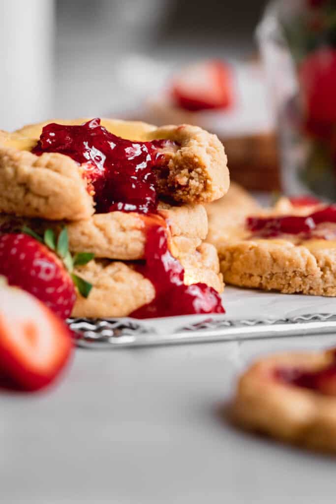 Strawberry cheesecake cookies on top of each other with strawberry compote running down.