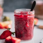 Strawberry Compote in a small Mason jar with a spoon in it.