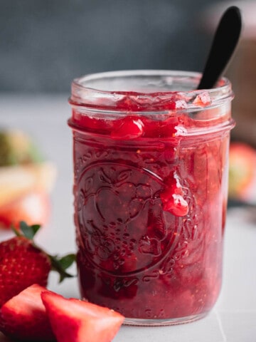 Strawberry Compote in a small Mason jar with a spoon in it.