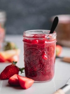 Strawberry Compote in a Mason jar with a small spoon in it.