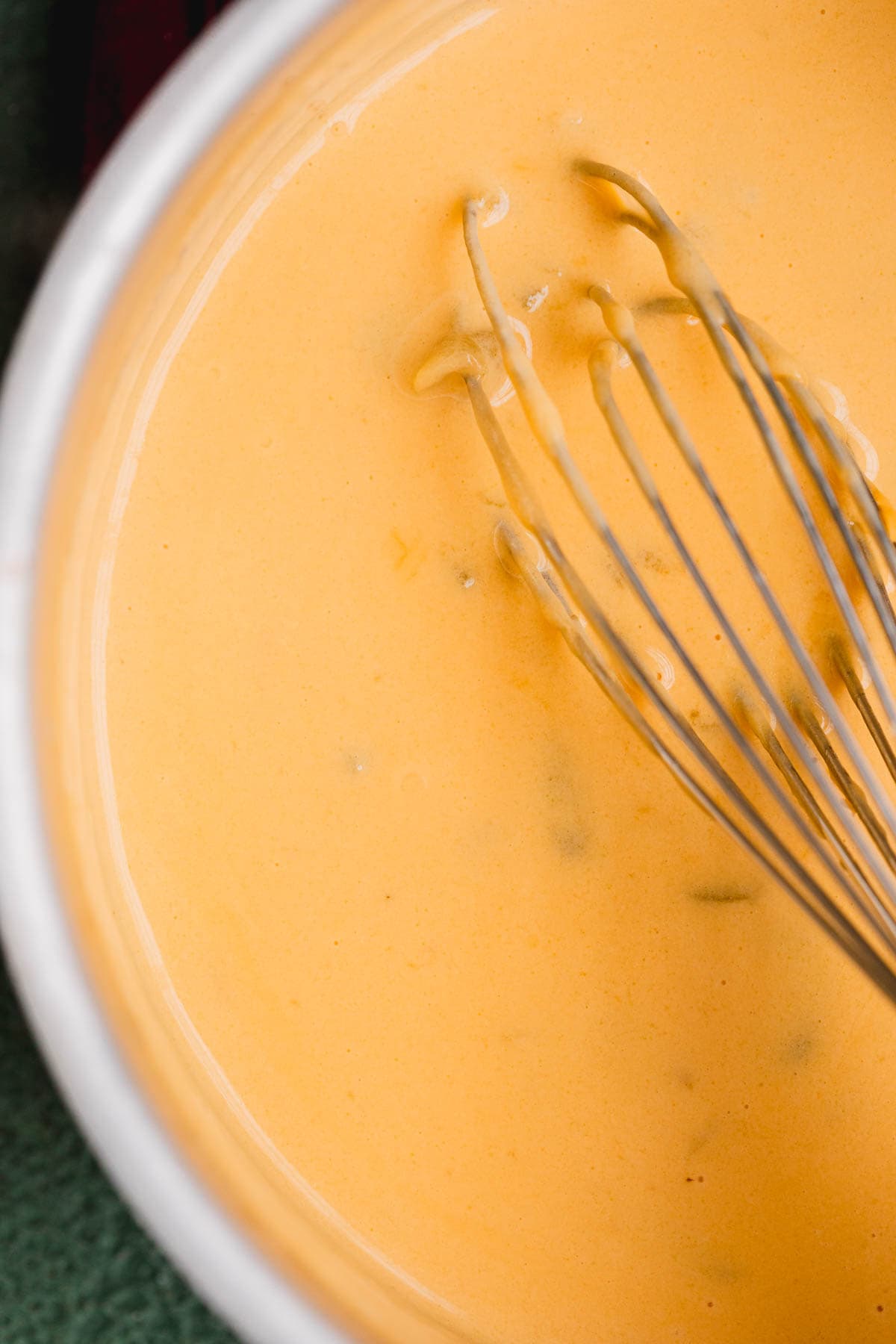 Cheese sauce in a pan with a whisk. 