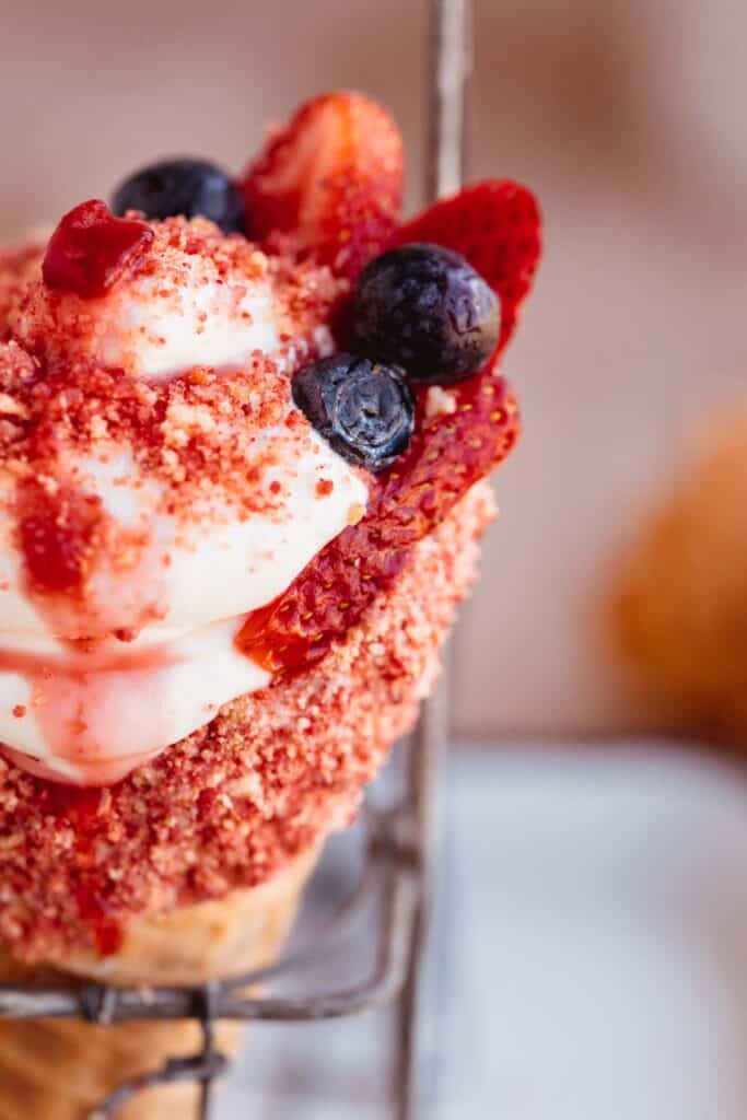 Strawberry crunch cheesecake cones topped with strawberry compote, fresh strawberries and blueberries.