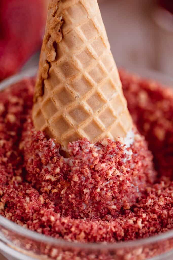 A bowl of strawberry crunch topping with a cone sticking out of it. 