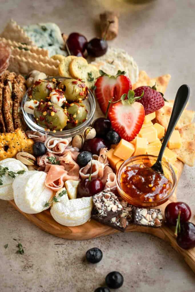 A charcuterie board filled with cheese olives, meat and the best crackers for a charcuterie board.