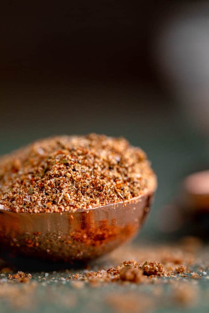 A mound of homemade chicken taco seasoning in a copper tablespoon.