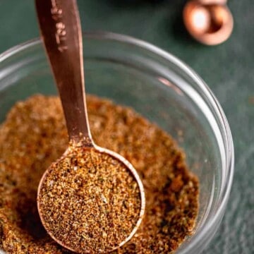A spice blend mixed together in a small dish with a copper tablespoon in it.