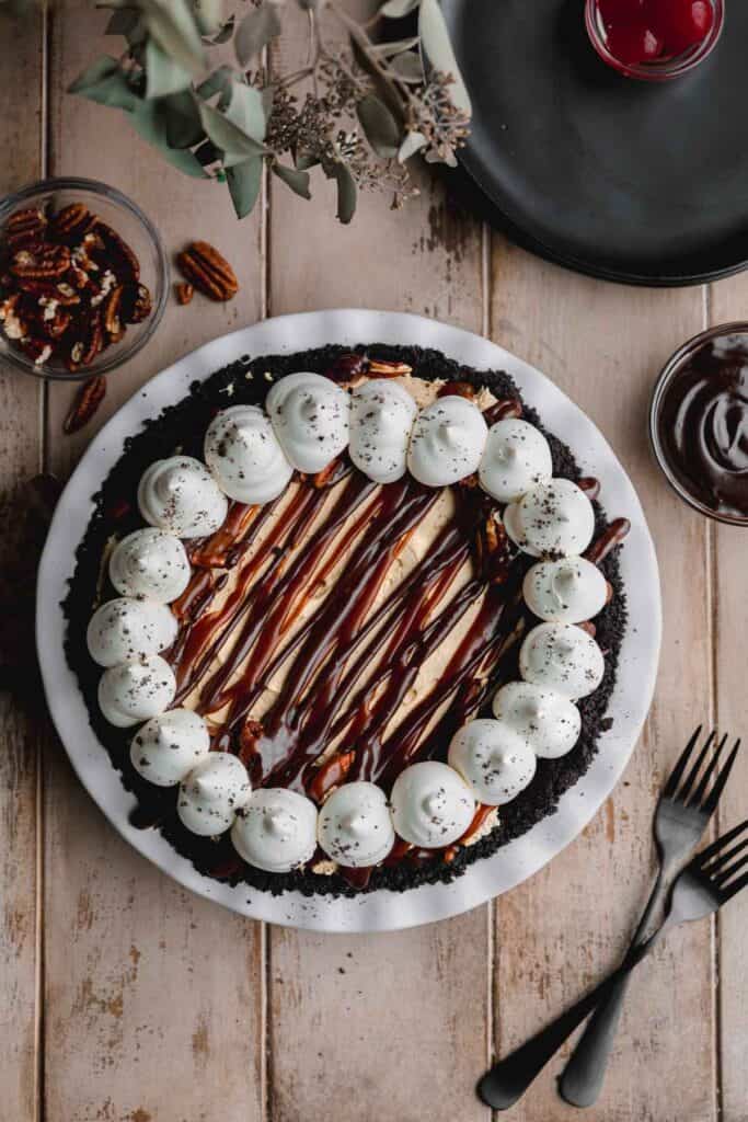A whole pie decorated with homemade caramel sauce, chocolate ganache and whipped cream.