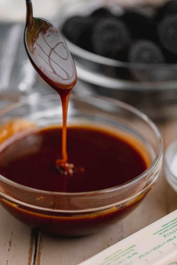 Homemade caramel sauce in a bowl with a spoon above it.