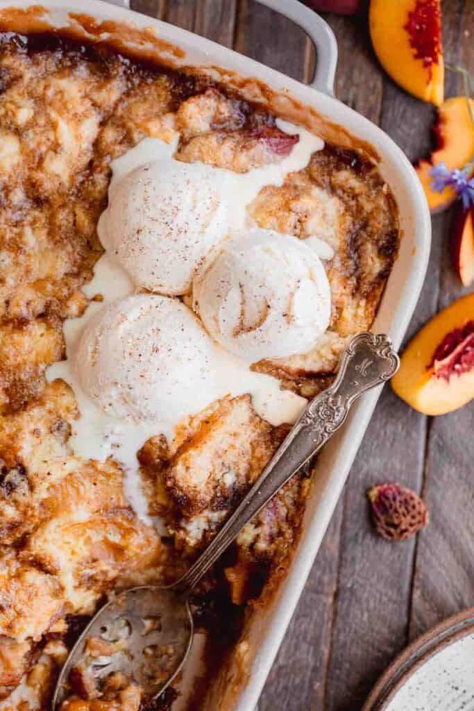 Peach Cobbler with Cake Mix topped with scoops of vanilla ice cream.