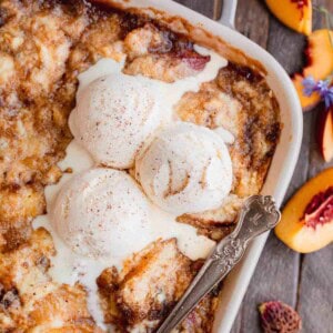 Peach Cobbler recipe with cake mix in a baking dish topped with scoops of vanilla ice cream.
