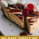 No bake Turtle Pie topped with chocolate ganache, caramel sauce and whipped cream with a cherry.