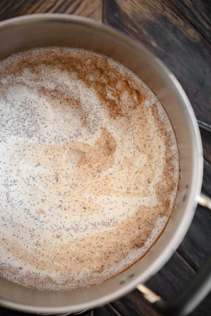 Cream heating with spices and sugar in a stock pot.
