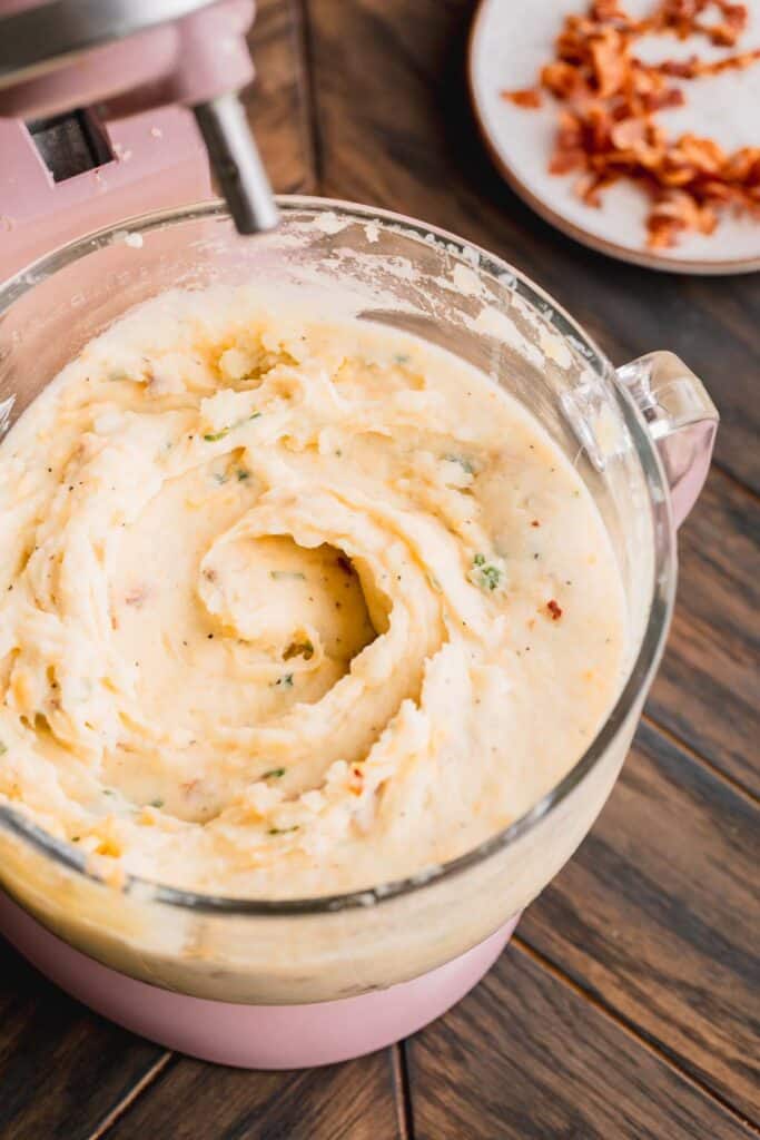 Loaded potato casserole all mixed up in the bowl of a mixer. 