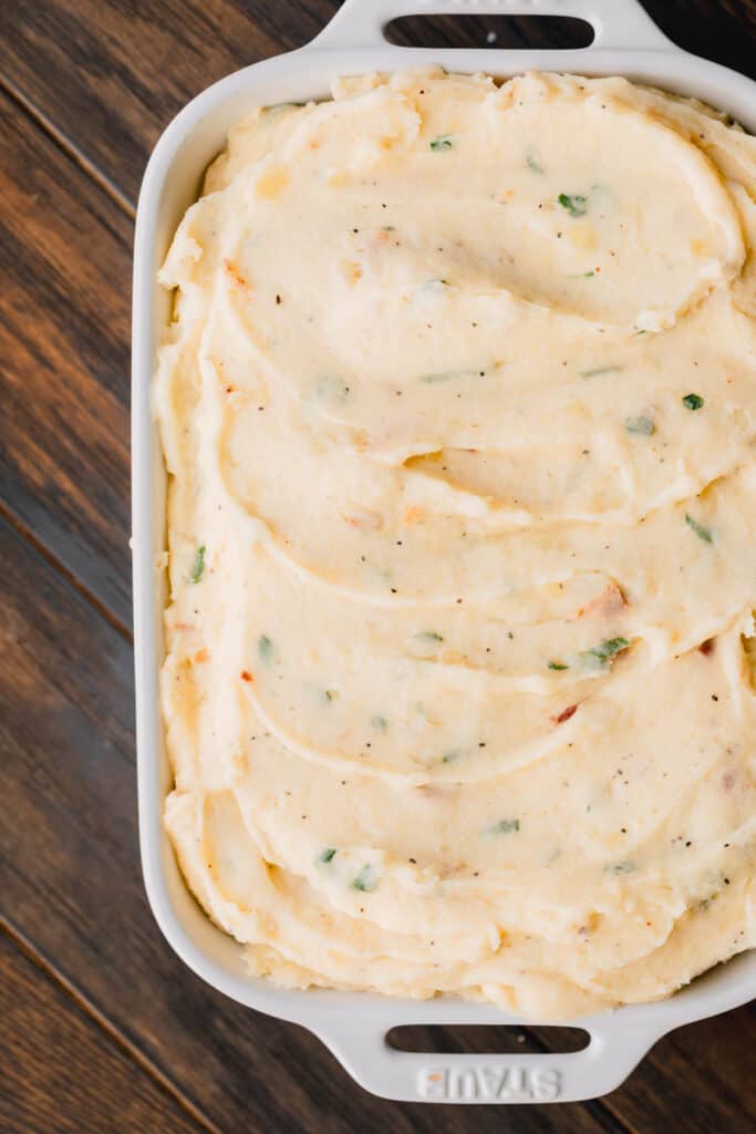 Loaded mashed potatoes in a ceramic baking dish.
