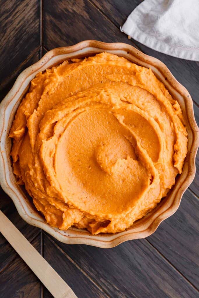 Whipped sweet potatoes in a pie pan on a wooden table.