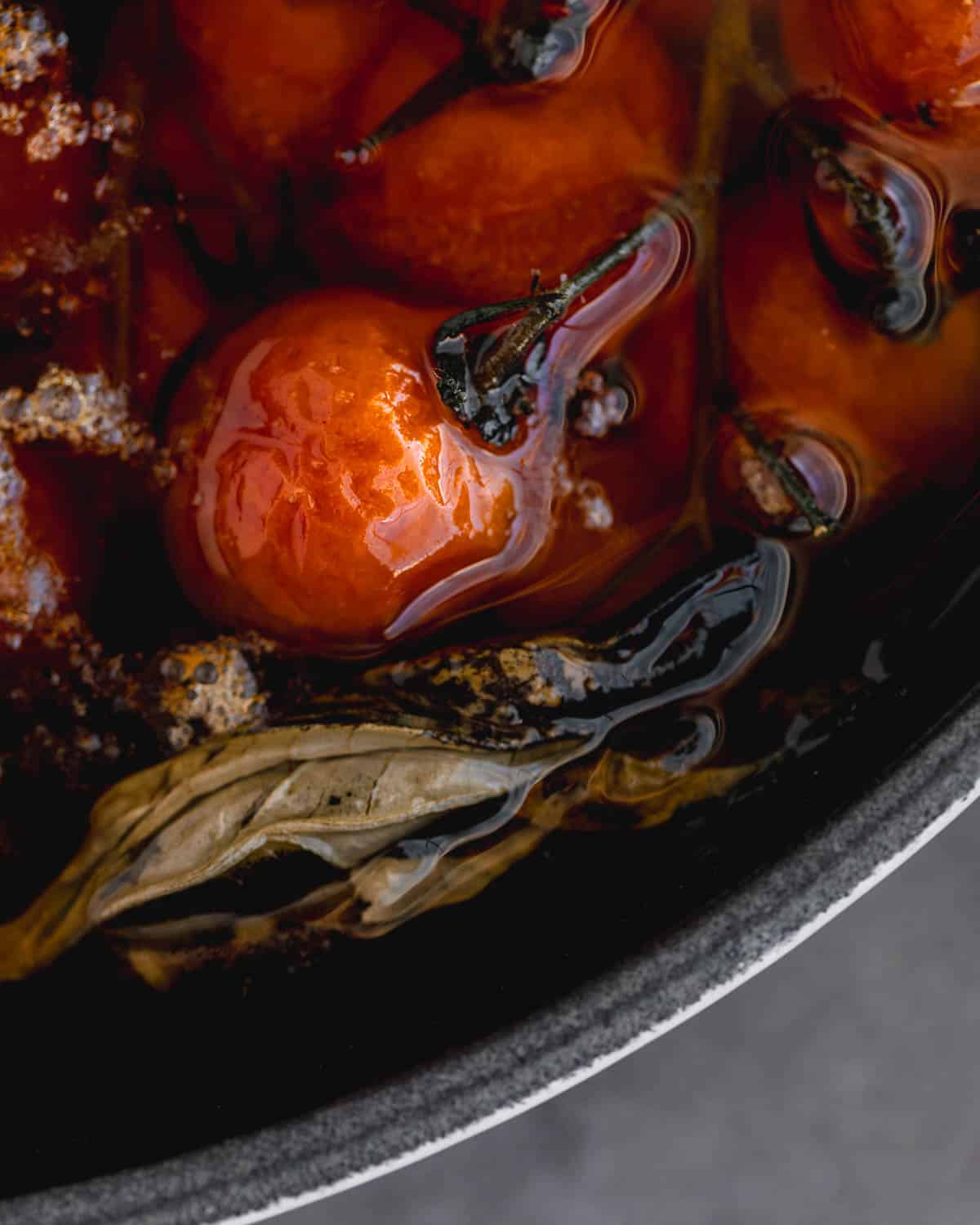 Cherry tomato confit with garlic in a cast iron skillet after being cooked. 