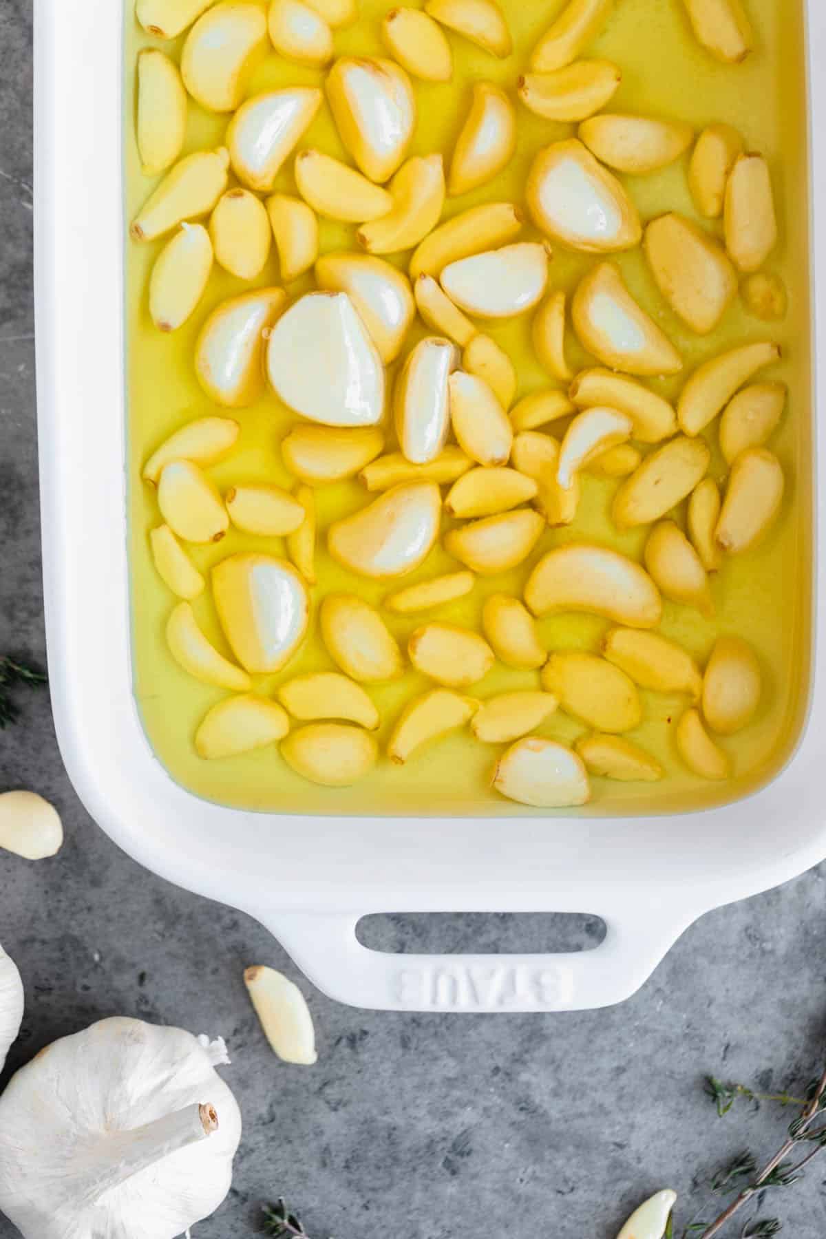 Garlic submerged in oil in a baking dish. 