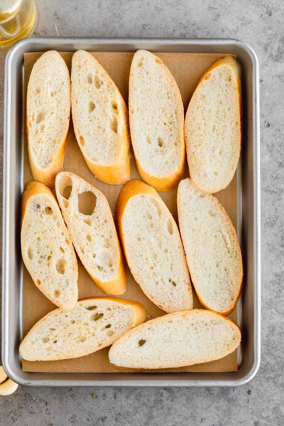 Toasted baguette slices on a sheet tray.
