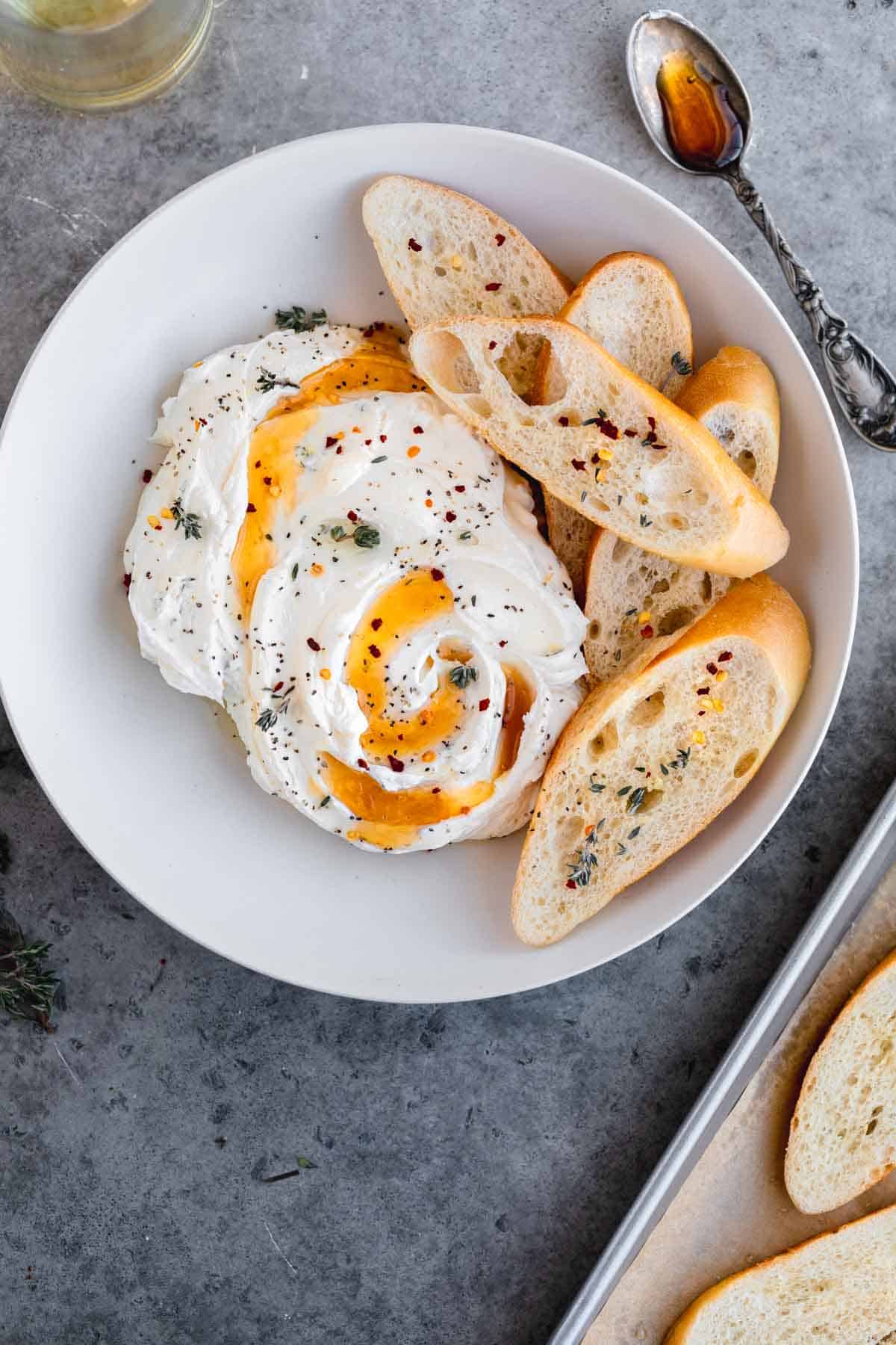 Whipped goat cheese appetizer with honey and crostini in a bowl.