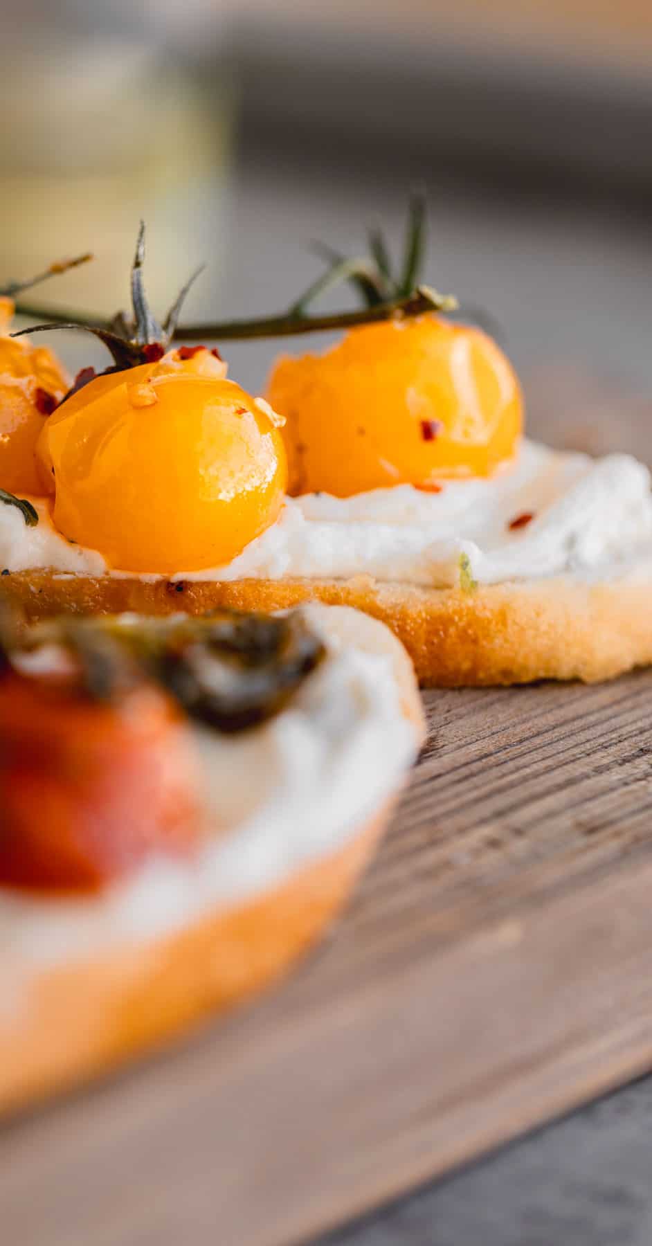 Whipped goat cheese appetizer spread on a crostini topped with tomato confit. 