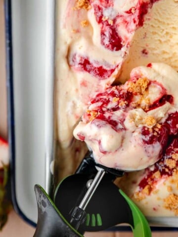 Strawberry Cheesecake Ice Cream in a loaf pan with a scooper getting some out.