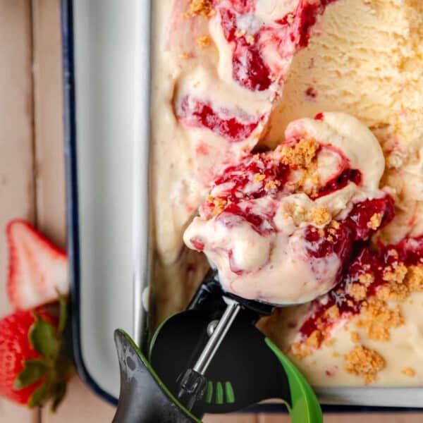 Strawberry Cheesecake Ice Cream in a loaf pan with a scooper getting some out.