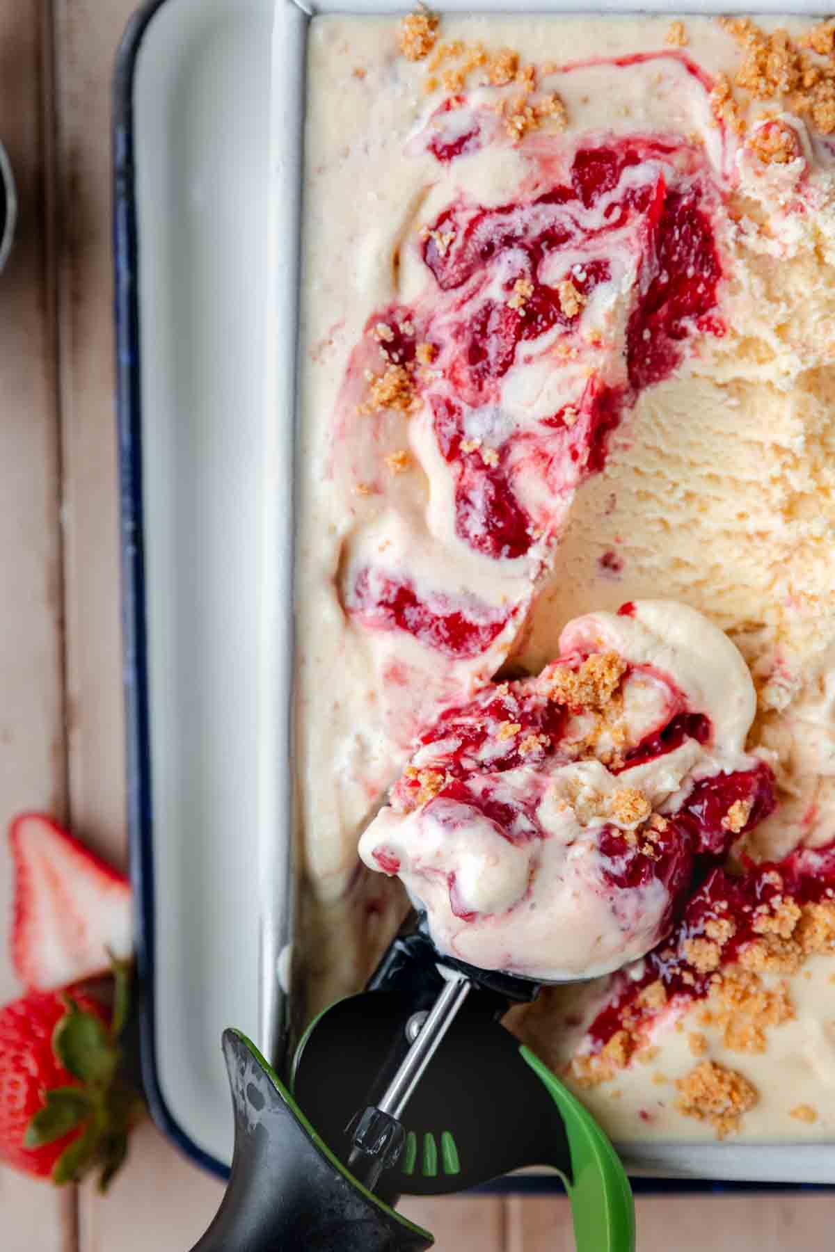Strawberry Cheesecake Ice Cream in a loaf pan with a scoop getting one scoop out. 