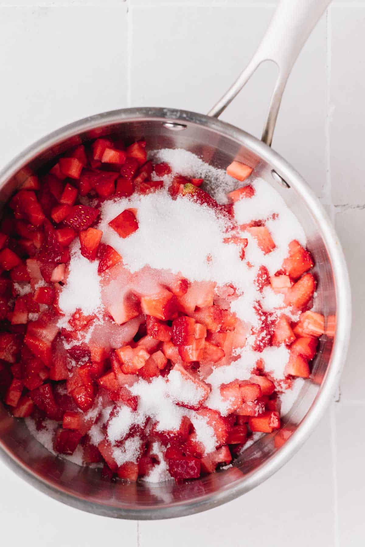 Strawberries, sugar and lemon juice cooking in a sauce pot.