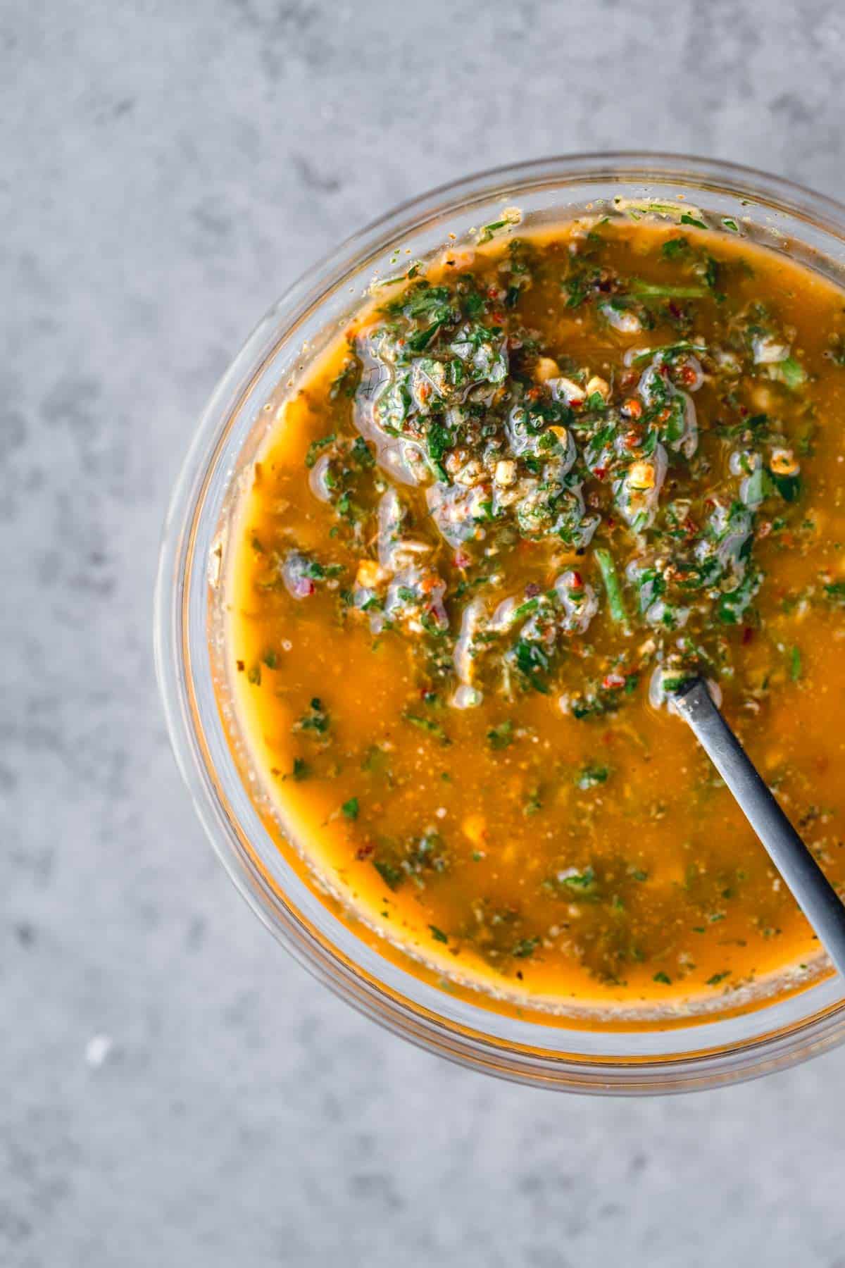 Chimichurri in a bowl with a spoon. 