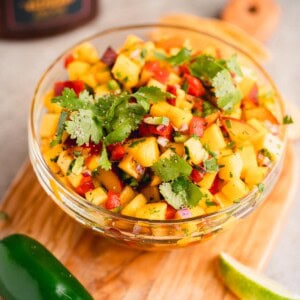 Peach Mango Salsa in a bowl on a cutting board.