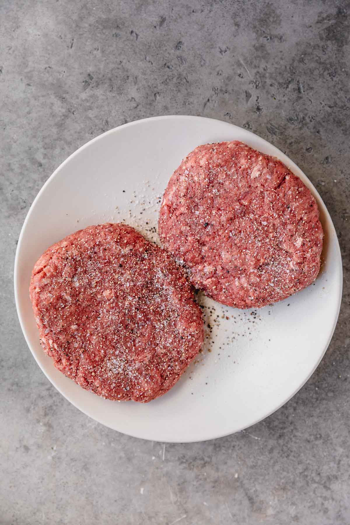 Seasoned wagyu ground beef patties on a plate. 