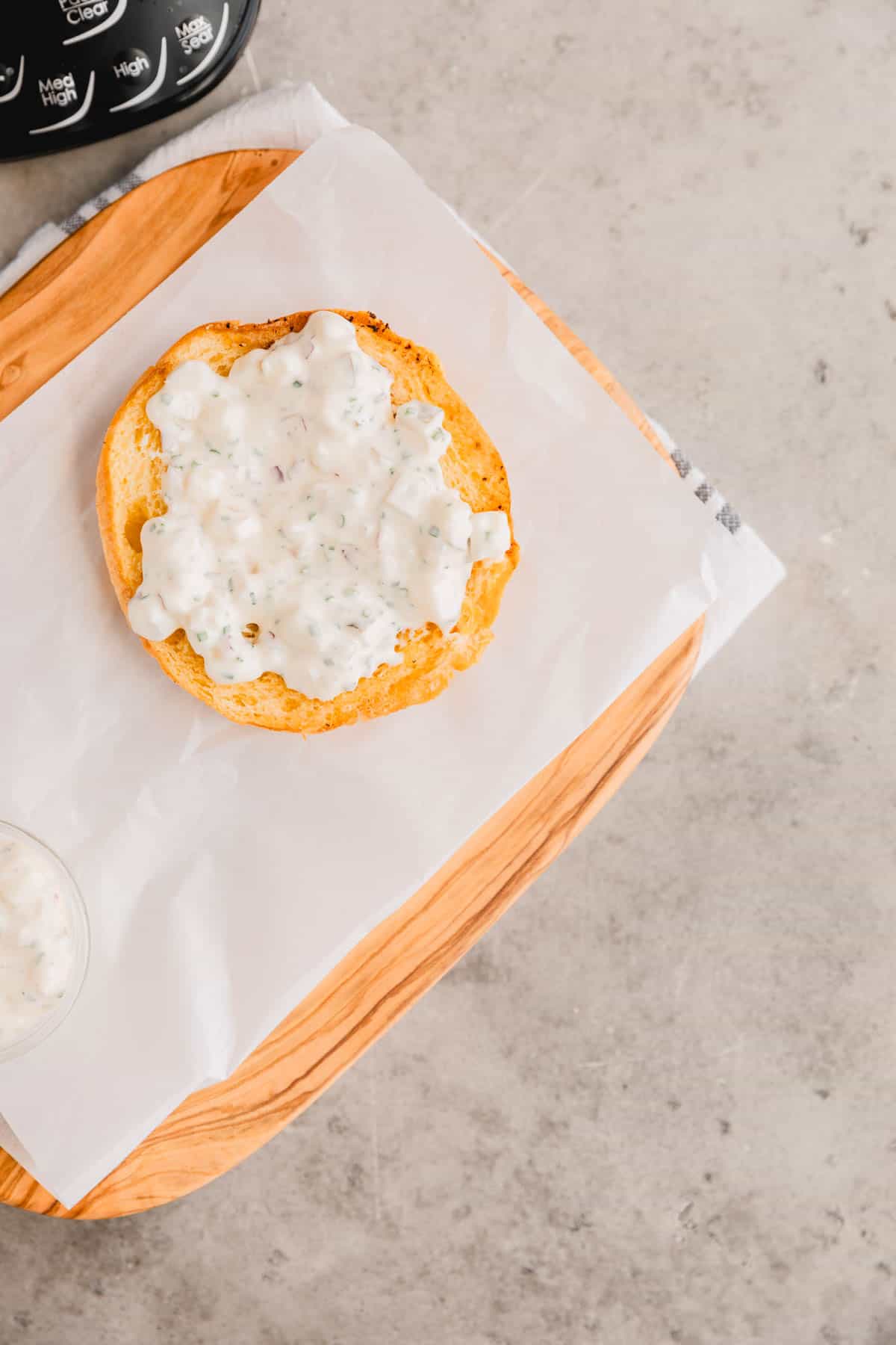 Truffle aioli spread on a hamburger bun on a cutting board. 