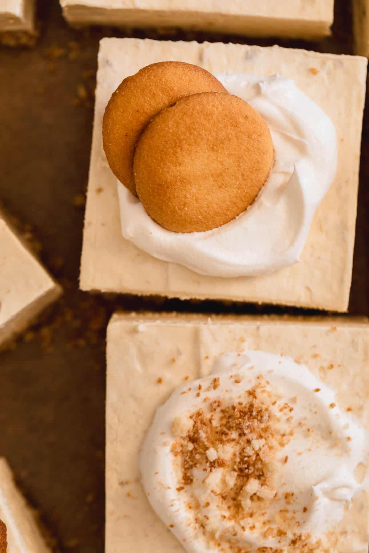 Banana Pudding Cheesecake Squares cut and topped with cream and cookies.