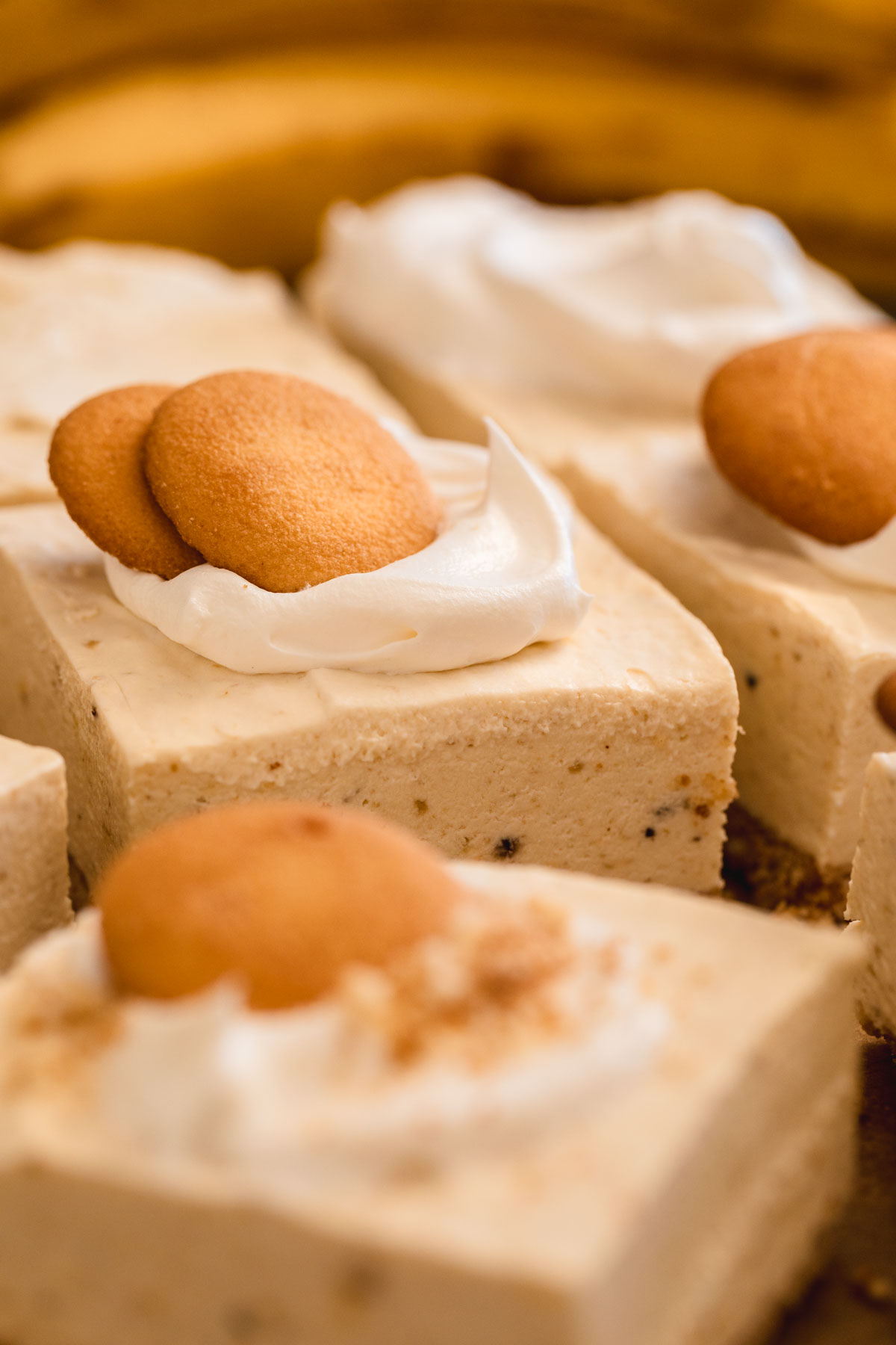 Banana Pudding Cheesecake Squares topped with whipped cream and Nilla Wafers.