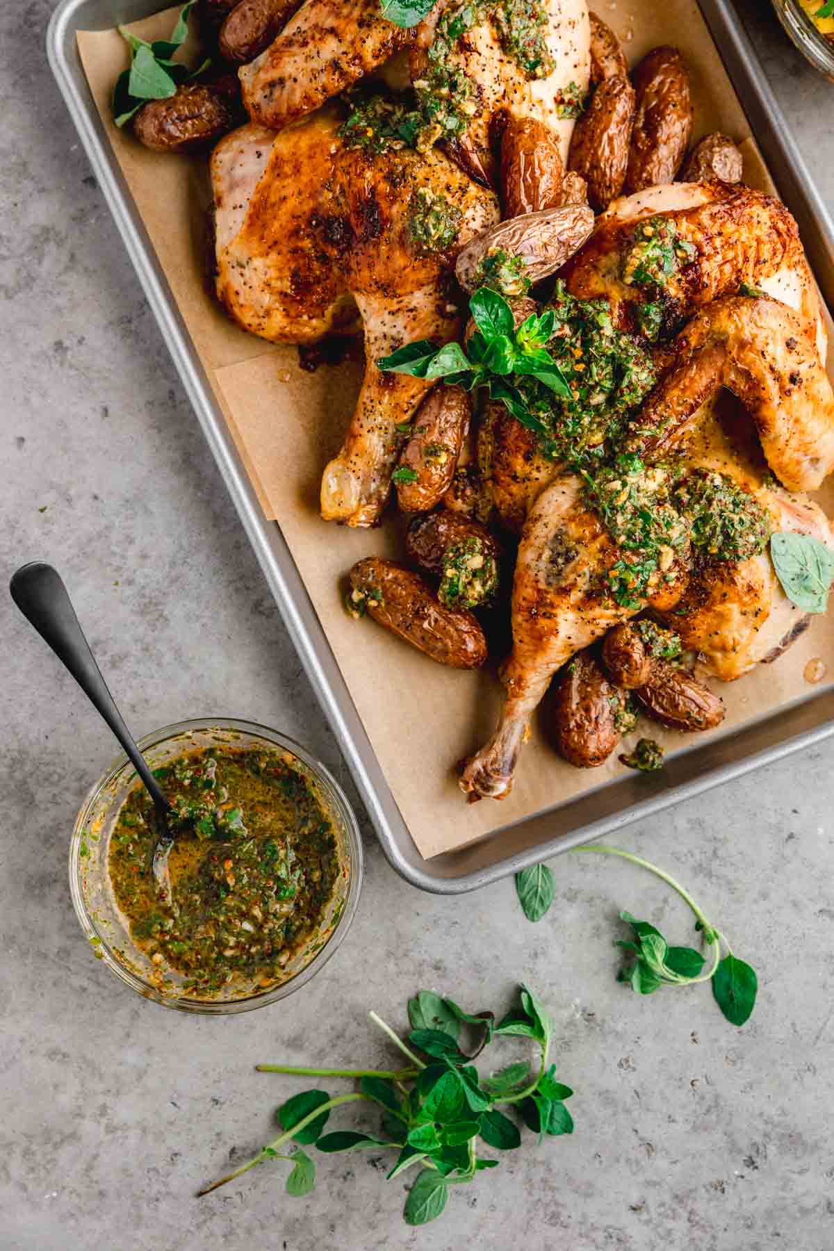 Roasted half chicken with chimichurri on a sheet tray. 