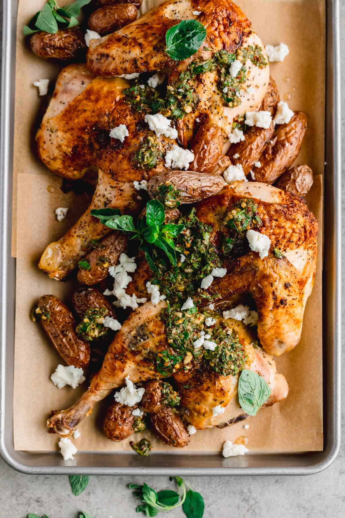 Roasted half chicken with chimichurri and feta on a sheet tray. 