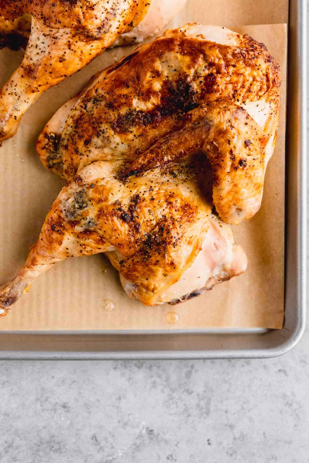 Roasted half chicken on a sheet tray. 