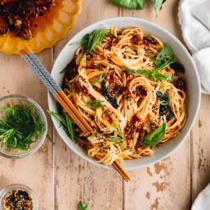 Chili Garlic Noodles in a bowl with chopsticks and basil.