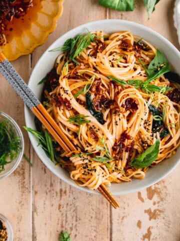 Chili Garlic Noodles in a bowl with chopsticks and basil.