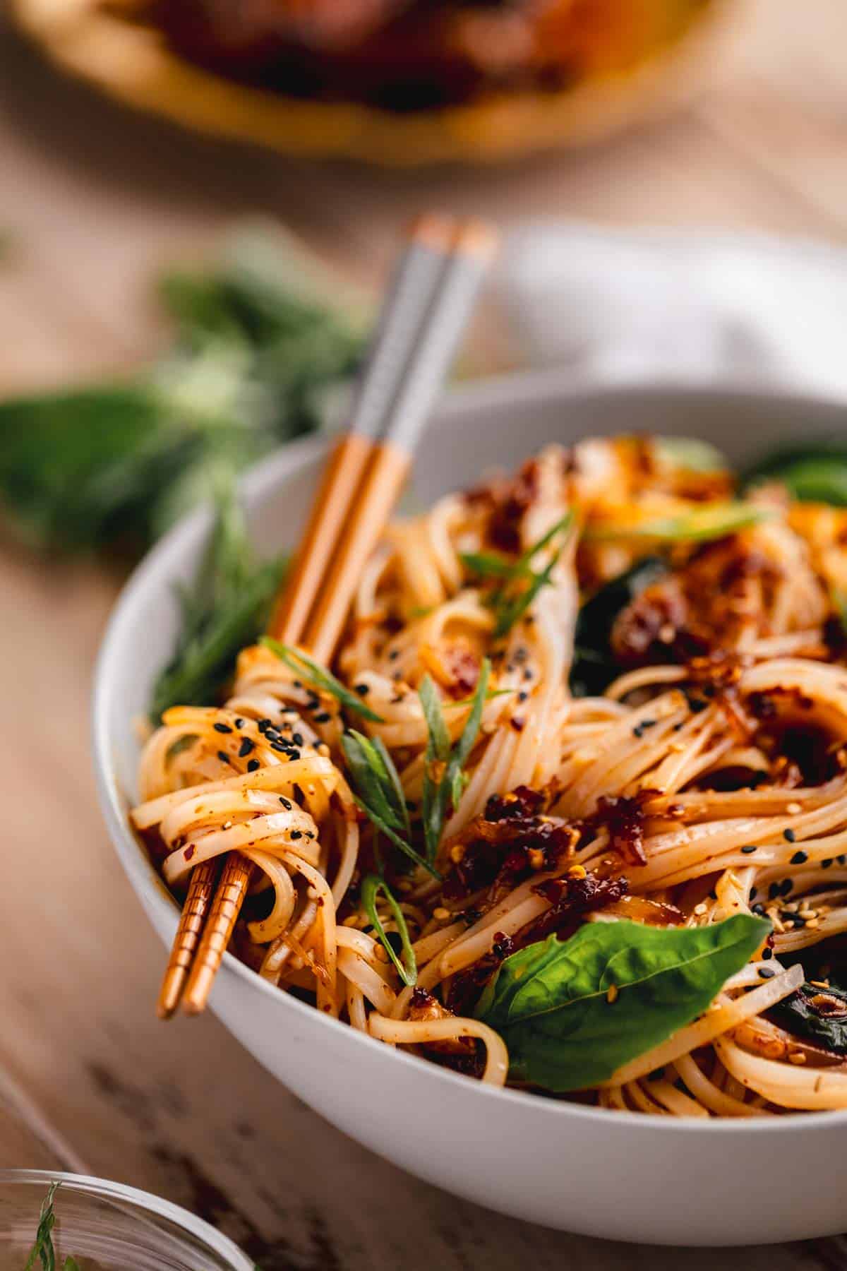 Chili Garlic Noodles in a bowl with noodles wrapped around chopsticks. 